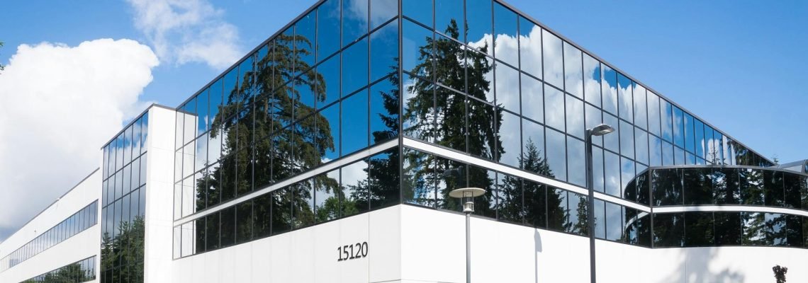 Contemporary office building in Redmond with reflective glass and lush greenery, captured on a sunny day.