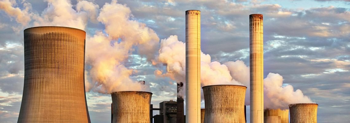 View of a power plant with smoke emissions under a cloudy sky, depicting industrial energy production.